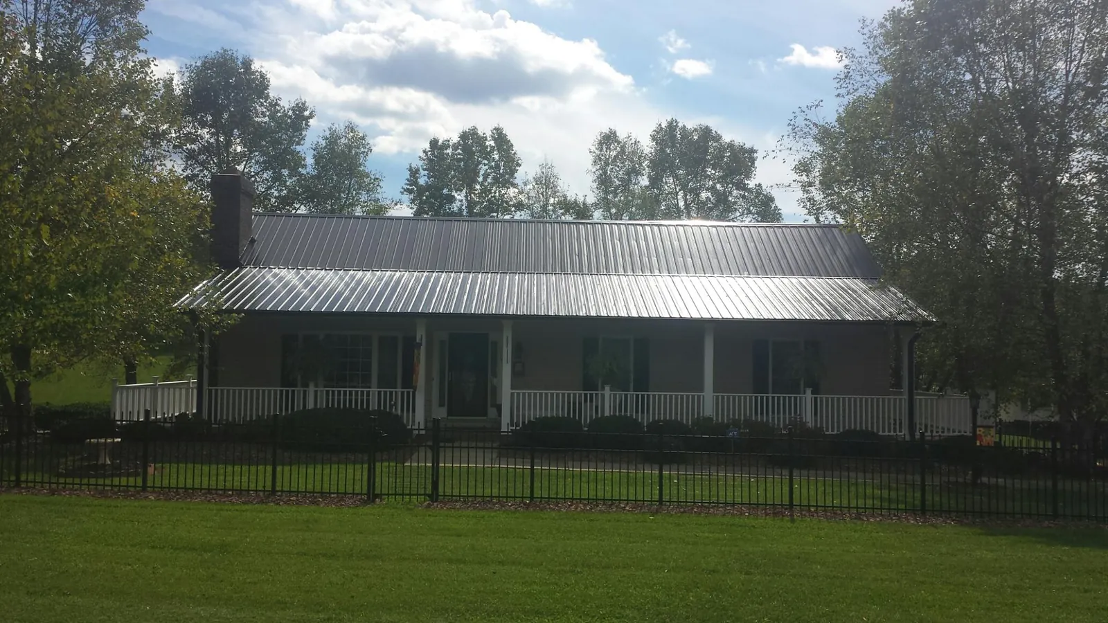 Gray metal roof on a brick ranch with a full width front porch — Gutter Guard Installation work by our crew in Hunter